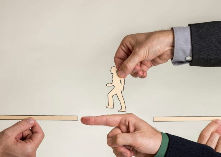 Three hands hold paper cutouts: one a gap, another a person walking, bridging the gap.